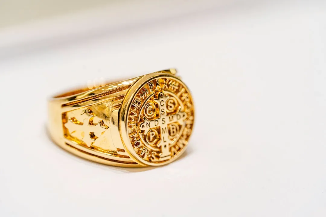 Gold Masonic ring displaying square and compass symbol on white background