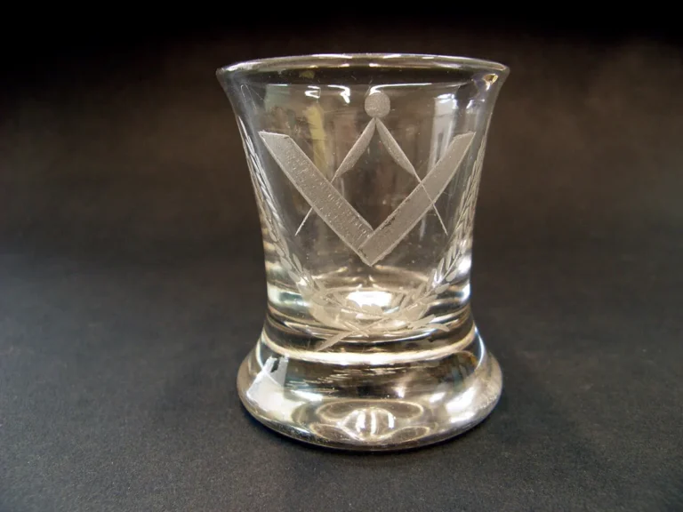 Engraved masonic symbolism on glass tumbler featuring compass, square, and fronds